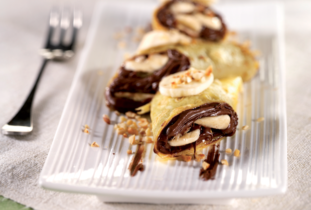 Crepes alla banana e nutella su piatto. Dessert goloso con frutta e cioccolato.