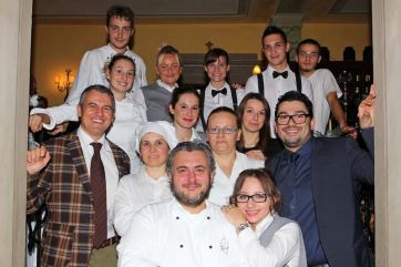 Gruppo di persone sorridenti, team ristorante. Chef, camerieri e personale di sala in posa. Ristorazione di qualità.