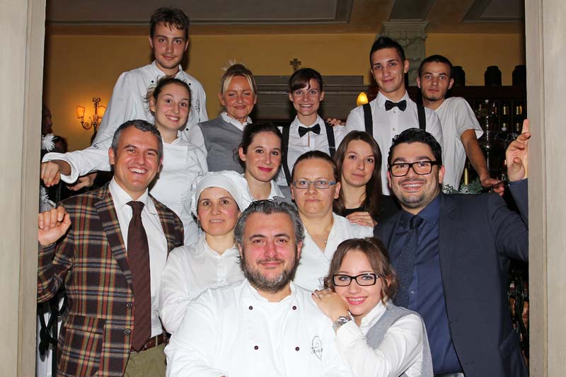 Gruppo di persone sorridenti, team ristorante. Chef, camerieri e personale di sala in posa. Ristorazione di qualità.