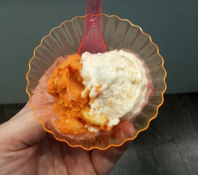 Gelato artigianale in coppetta: arancia e crema. Cucchiaio rosa.