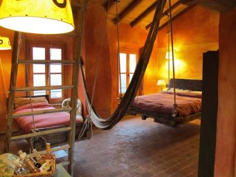 Camera con letto sospeso, amaca e scala in legno. Design d'interni rustico e accogliente. Arredamento originale.