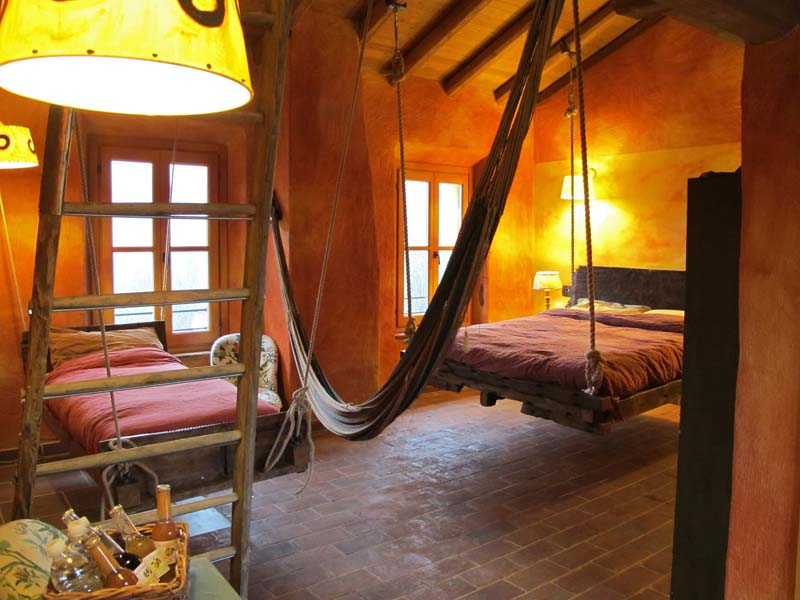 Camera con letto sospeso, amaca e scala in legno. Design d'interni rustico e accogliente. Arredamento originale.