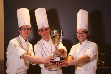 Team Italia pasticceria vince coppa. Chef italiani con trofeo, campioni nazionali pasticceria e cioccolato.