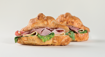 Croissant salato farcito con prosciutto, formaggio e insalata. Snack gustoso.