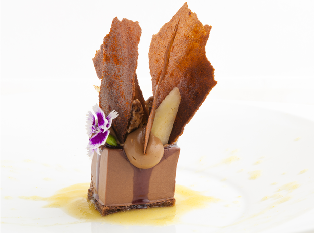 Dolce al cioccolato gourmet con decorazioni floreali e croccante. Dessert raffinato.
