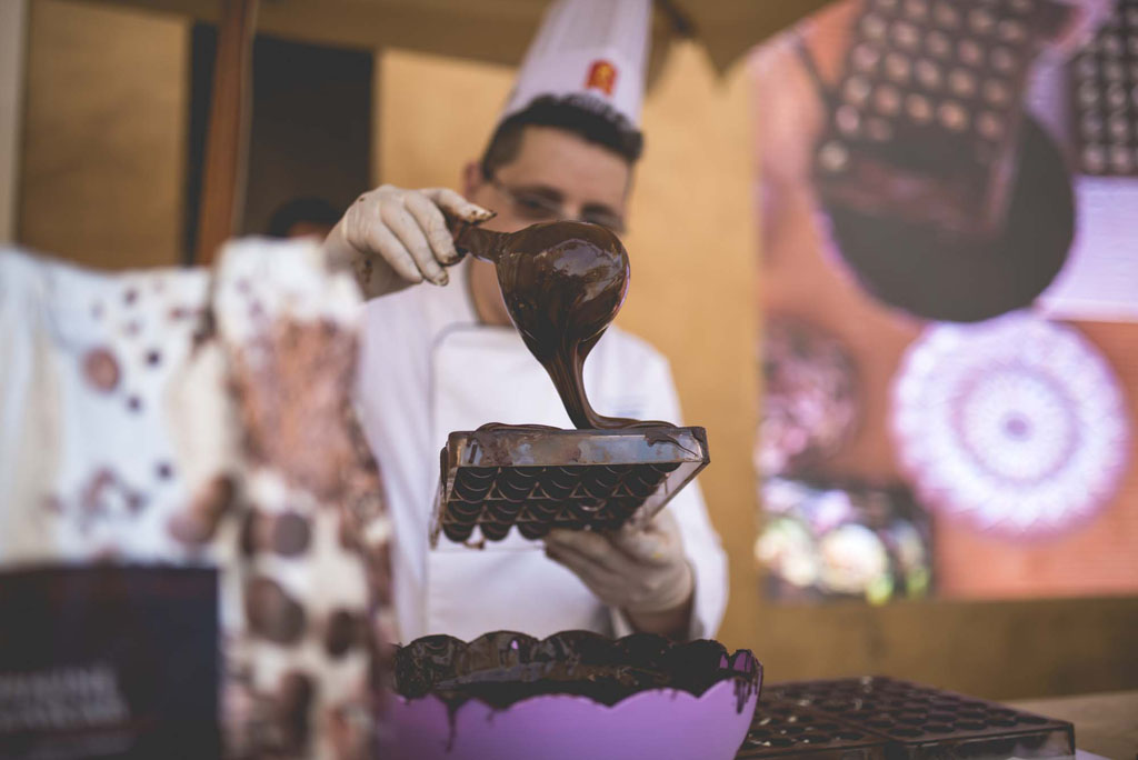 Chef versa cioccolato fuso in stampo. Dolci artigianali, cioccolateria.