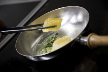 Capesante in padella. Cucina gourmet, ricetta con erbe aromatiche. Chef al lavoro.