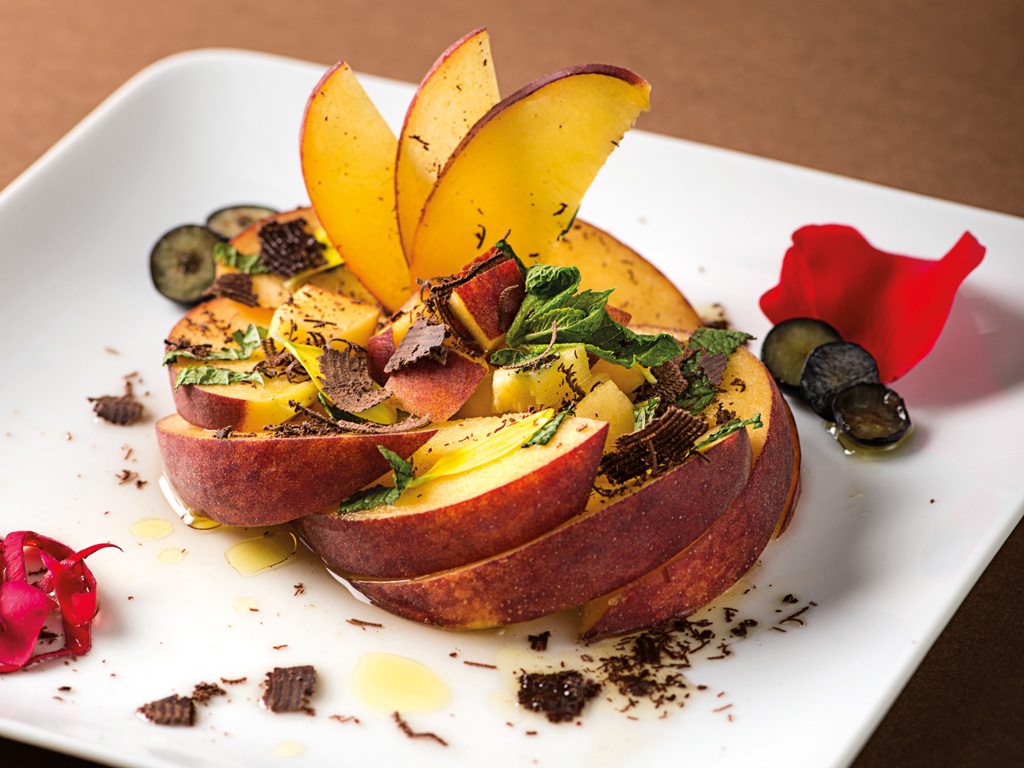 Bellini gourmet: pesca fresca a fette con cioccolato, mirtilli e menta. Dessert estivo elegante.