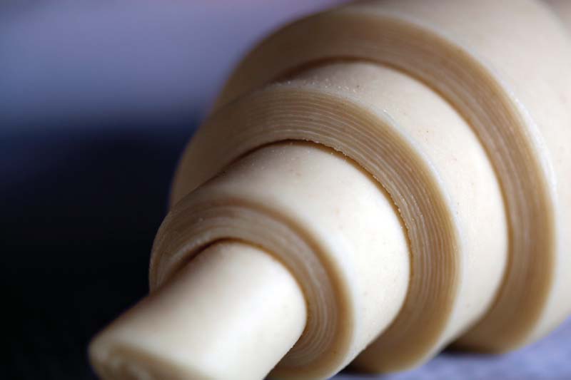 Primo piano di croissant sfogliato crudo. Pasta per croissant, viennoiserie.