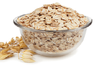 Fiocchi d'avena in ciotola di vetro. Cereale integrale per colazione sana e ricca di fibre.