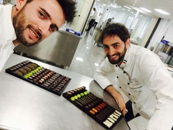 Cioccolatieri italiani sorridenti con cioccolatini artigianali assortiti. Maestri cioccolatieri al lavoro.