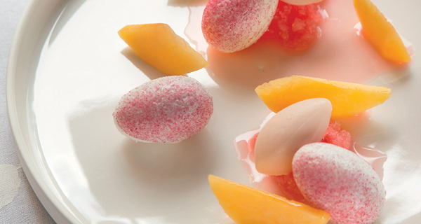 Dessert gourmet: pesche, sorbetto rosa e palline zuccherate. Delizia culinaria.