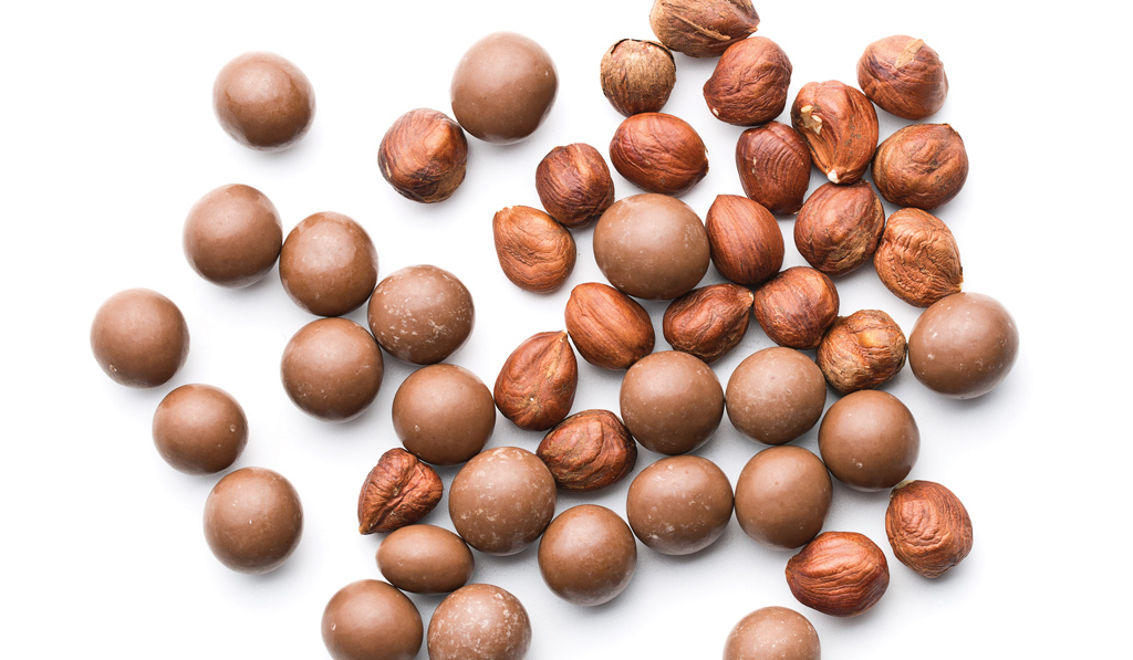 Cioccolatini e nocciole. Dolciumi con nocciole intere e palline di cioccolato al latte.