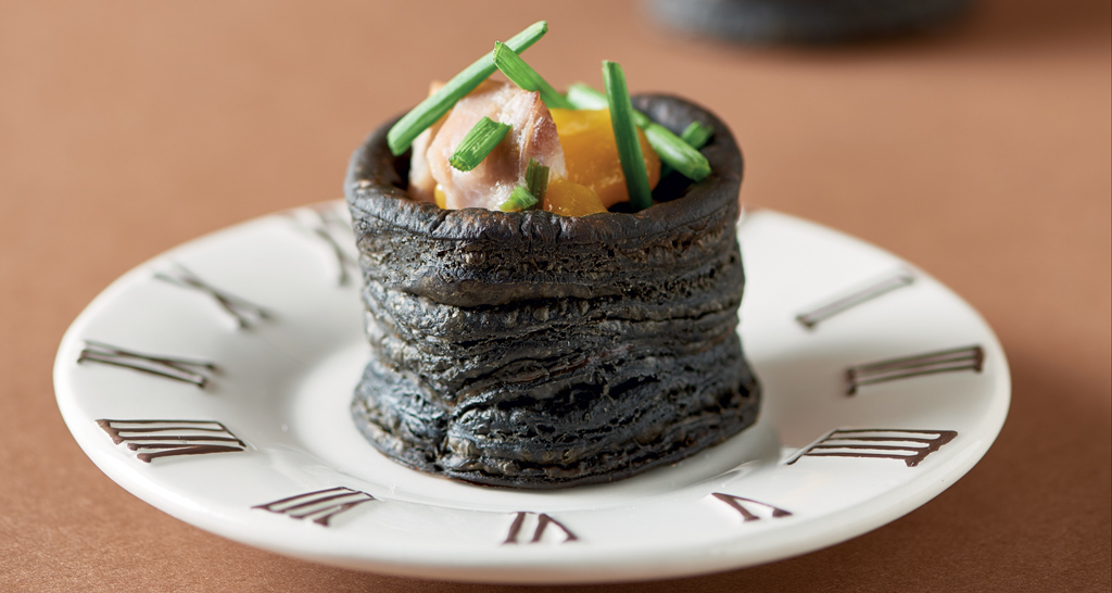 Piatto gourmet con nero di seppia. Tartare di pesce, guarnizione di erba cipollina. Ricetta creativa.