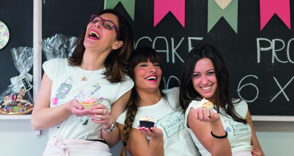 Tre donne sorridenti con cupcake. B Sweet Ok, pasticceria artigianale.