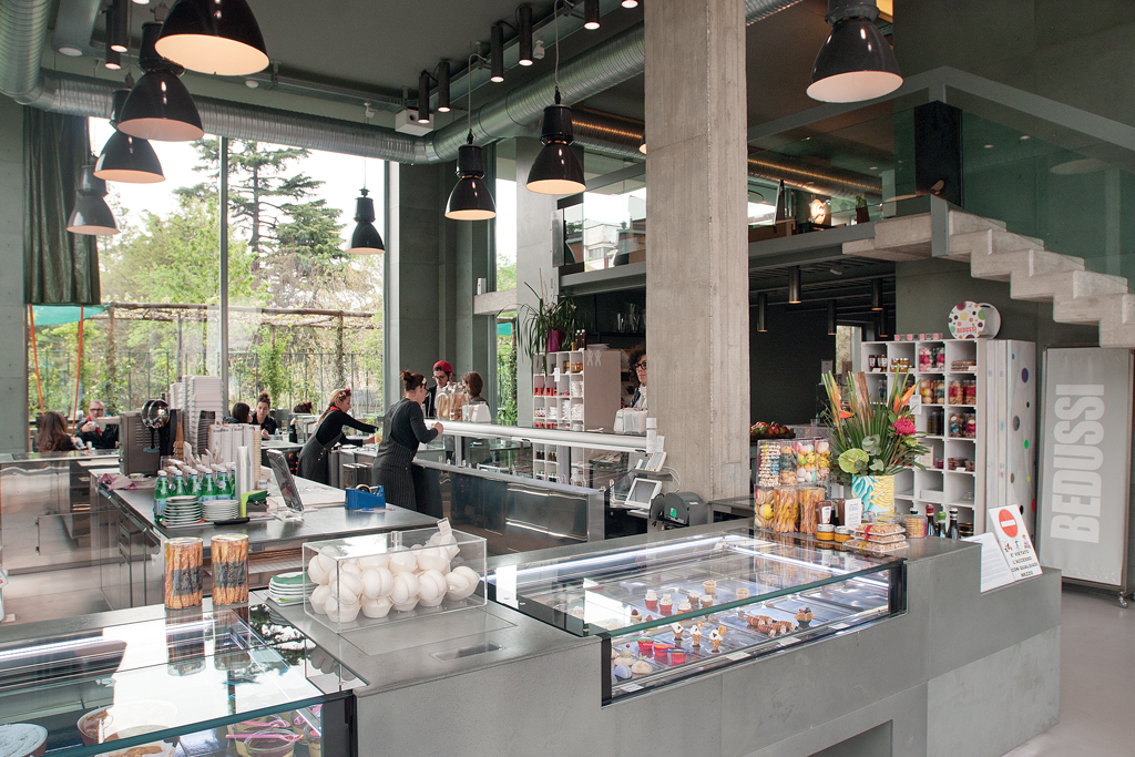 Interno del caffè Bedussi: design moderno, vetrine dolci, lampade a sospensione, atmosfera accogliente.