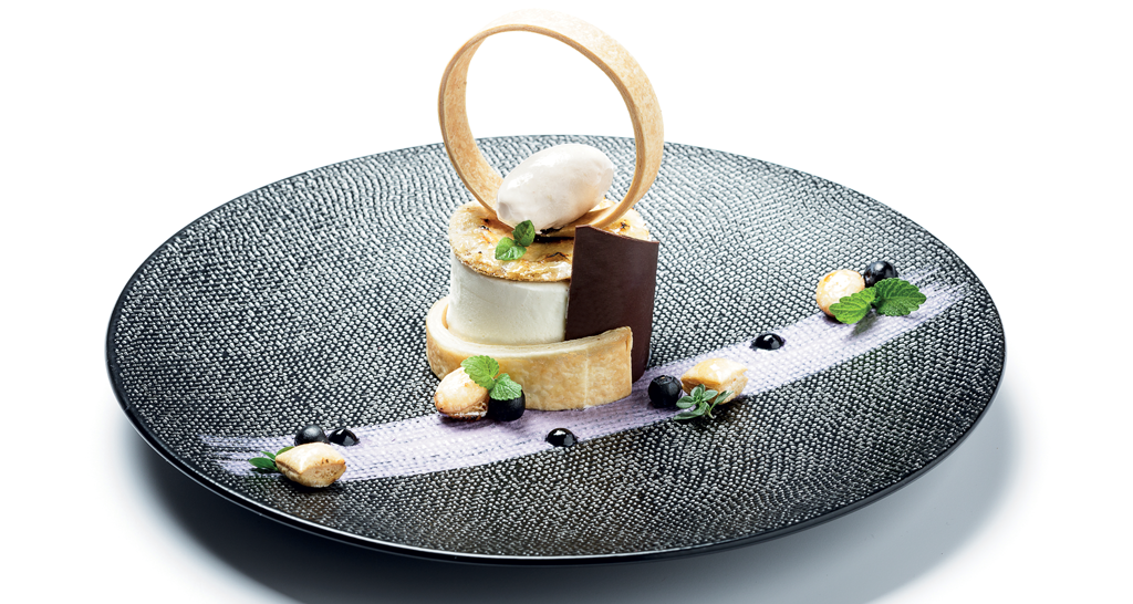 Dessert gourmet su piatto decorato. Dolce con gelato, cioccolato, mirtilli e menta. Alta cucina, pasticceria creativa.