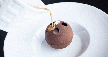 Dessert tiramisù sferico al cioccolato. Salsa versata su dolce gourmet.