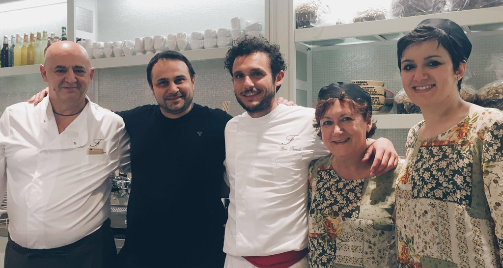 Team Pasticceria Francesco. Gruppo sorridente di pasticceri e staff. Dolci artigianali e professionalità.