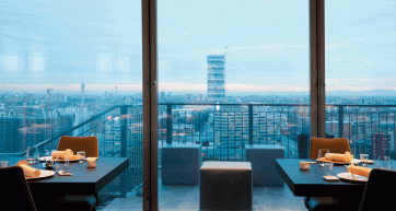 Ristorante Unico Milano: vista panoramica sulla città. Tavoli apparecchiati, atmosfera elegante e cucina gourmet.