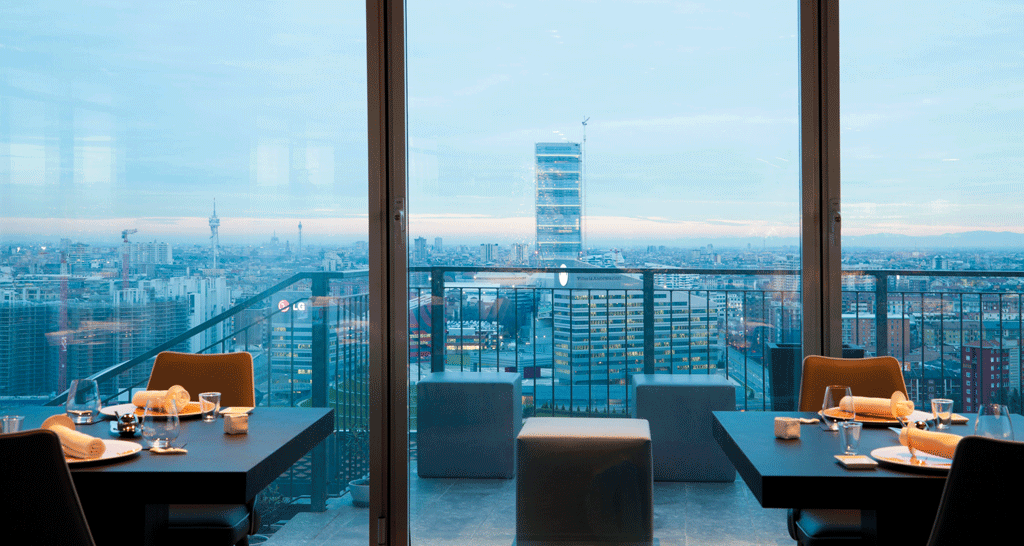 Ristorante Unico Milano: vista panoramica sulla città. Tavoli apparecchiati, atmosfera elegante e cucina gourmet.