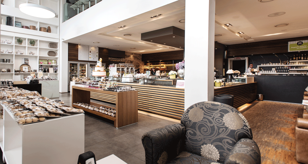 Interno elegante di pasticceria e caffetteria. Arredamento moderno, vetrine con dolci e torte. Design accogliente.