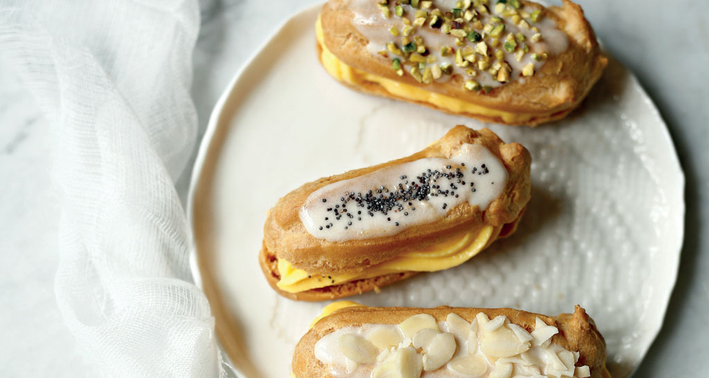Éclair assortiti su piatto: pistacchio, semi di papavero, mandorle. Pasticceria francese.