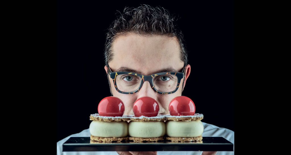 Chef con dolci. Pasticceria artigianale con mousse e glassa rossa. Dessert gourmet.