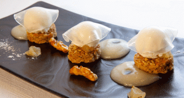 Dolce di pere gourmet. Dessert con gelato, caramello e decorazioni su piatto nero. Cucina raffinata.