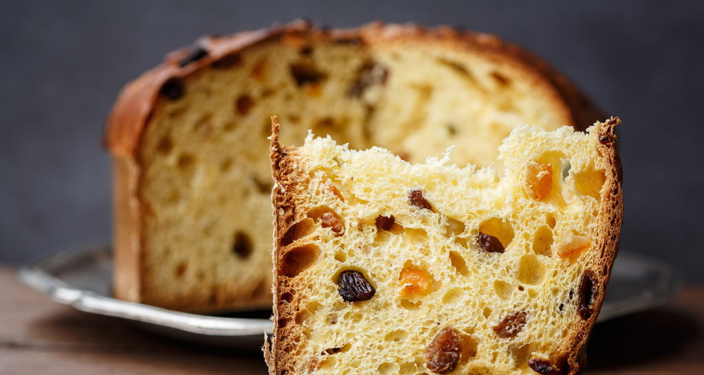 Fetta di panettone artigianale con uvetta e canditi. Dolce tipico natalizio italiano.