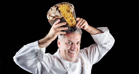 Chef sorridente con panettone in testa. Dolce natalizio artigianale italiano.