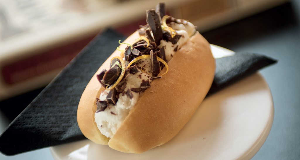 Dolce panino con panna, cioccolato fondente e scorza d'arancia. Dessert creativo e goloso.