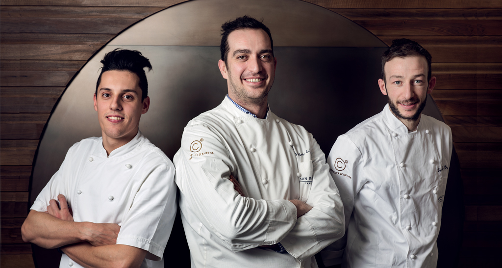 Tre chef sorridenti in divisa bianca. Ristorante di alta cucina, team di cucina.
