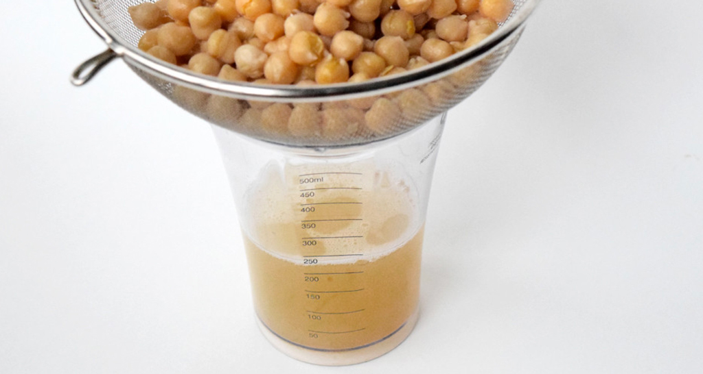 Aquafaba: liquido di cottura dei ceci. Ceci scolati in un colino, sopra un misurino.