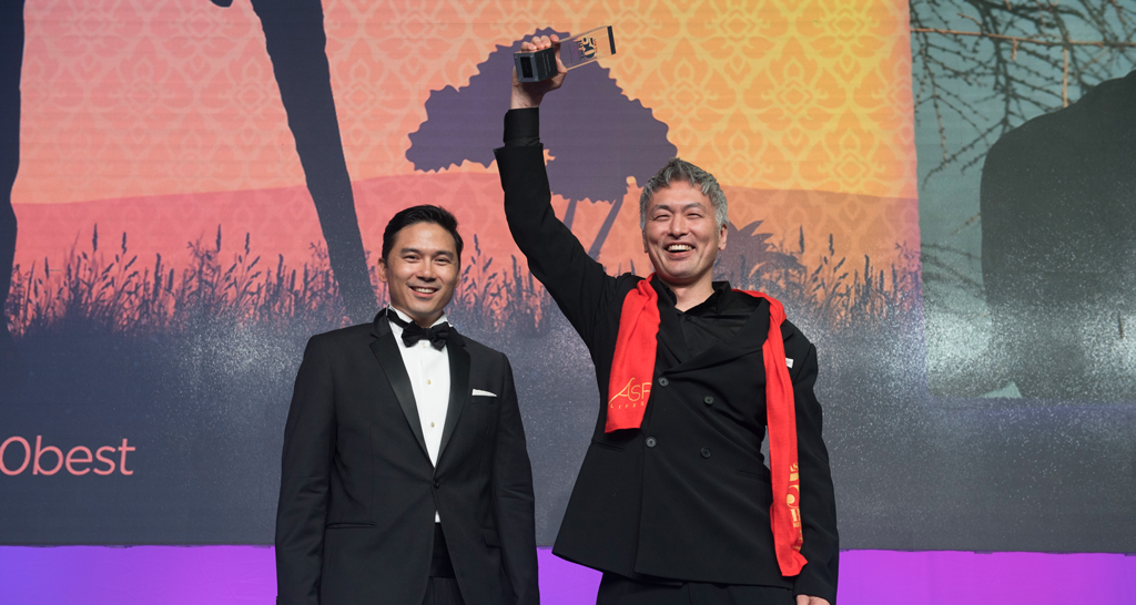 Due uomini in smoking ricevono un premio. Vincitore sorridente con trofeo. Evento premiazione.