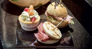 Assortimento di finger food: tartelletta con gambero, mini hamburger e panino con salame. Aperitivo sfizioso.