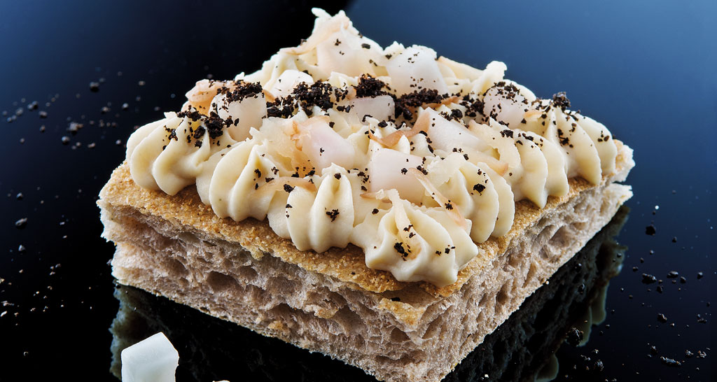 Focaccia gourmet con crema, cocco e polvere di olive. Specialità culinaria, cibo da forno.