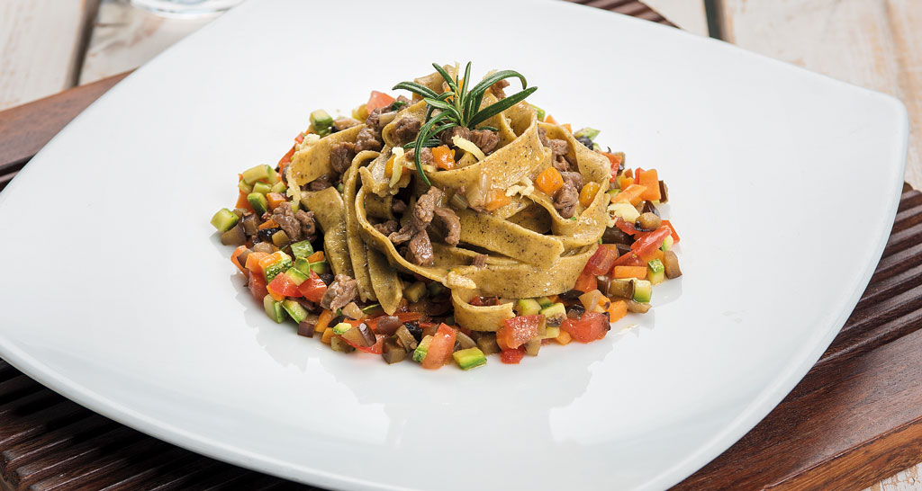 Tagliatelle fresche con ragù di carne e verdure miste. Piatto gourmet.