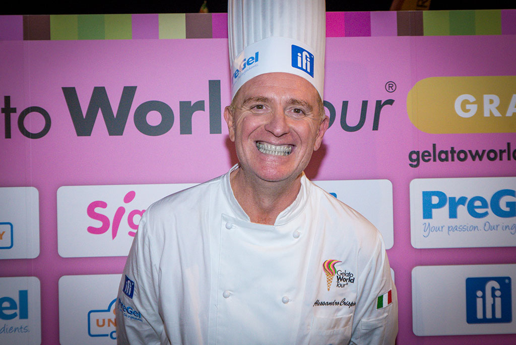 Alessandro Crispini, vincitore del Gelato World Tour. Chef italiano sorridente con divisa bianca e cappello da cuoco.