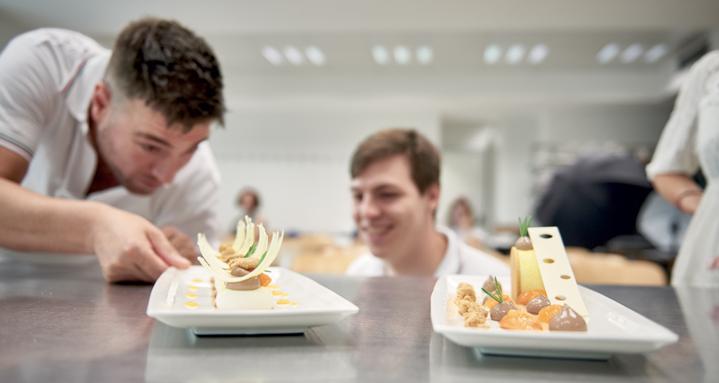 Chef presenta dessert gourmet. Pasticceria creativa, decorazioni elaborate. Alta cucina, arte culinaria.