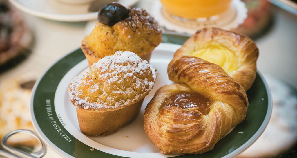 Dolci da colazione: brioche con crema, tortine con zucchero a velo e frutta candita.
