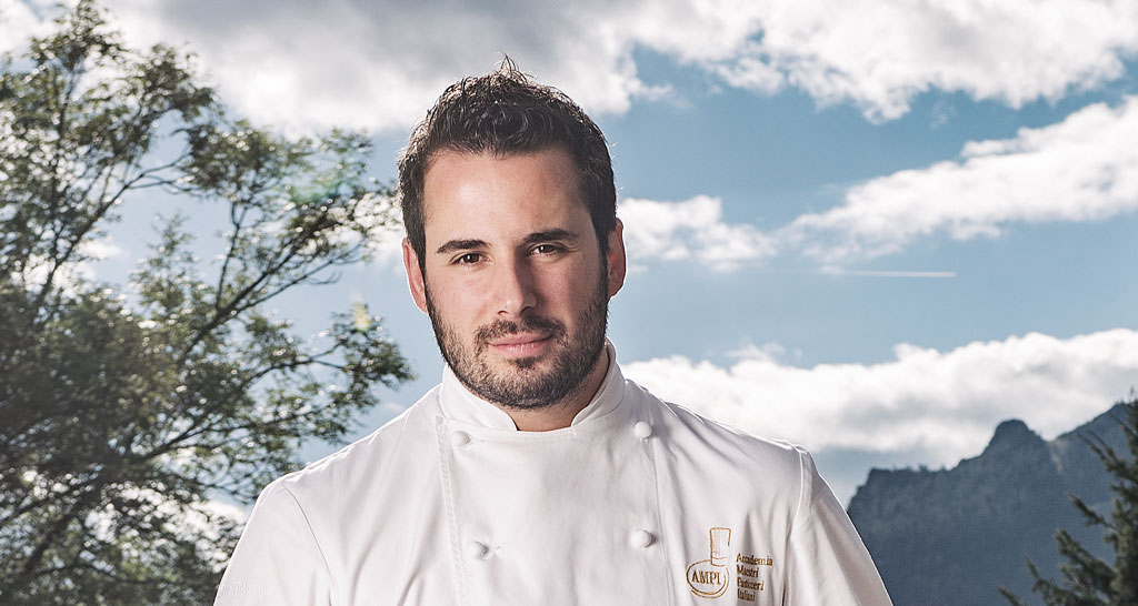 Ritratto chef pasticcere in divisa bianca. Natura e cielo sullo sfondo.