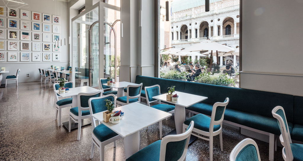 Interno elegante del Ristorante Garibaldi a Vicenza. Tavoli bianchi e sedie blu. Vista sulla Basilica Palladiana.