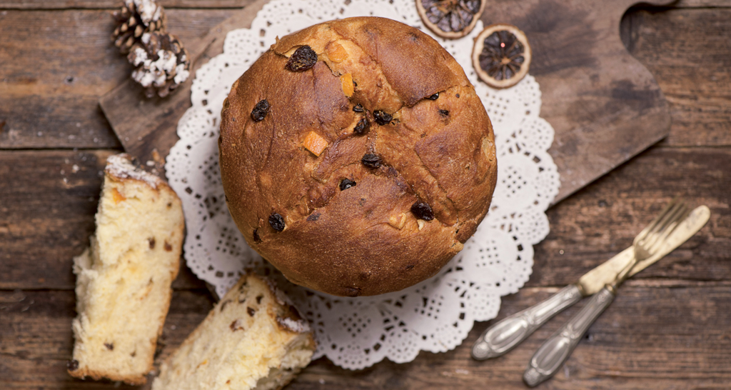 Panettone artigianale su tagliere di legno. Dolce natalizio con canditi e uvetta, ideale per le feste.