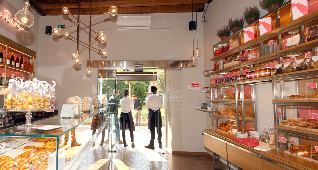 Interno di La Pâtisserie des Rêves: vetrina dolci, scaffali con prodotti da forno, illuminazione design.