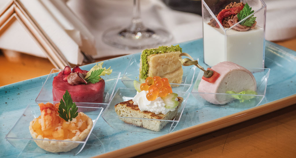 Assortimento di finger food gourmet su vassoio. Tartine, tartare, mousse e dolci monoporzione per aperitivo elegante.