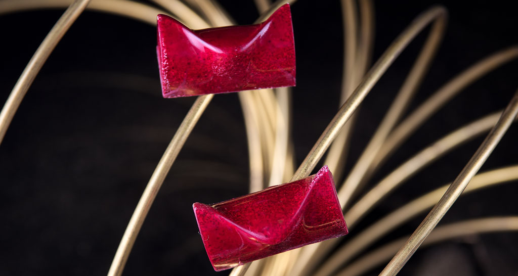 Praline artigianali rosse su fili dorati. Dolci gourmet, cioccolatini di lusso.