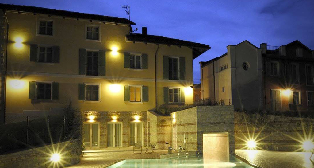 Villa Amelia illuminata di notte. Architettura elegante con piscina. Design esterno raffinato.