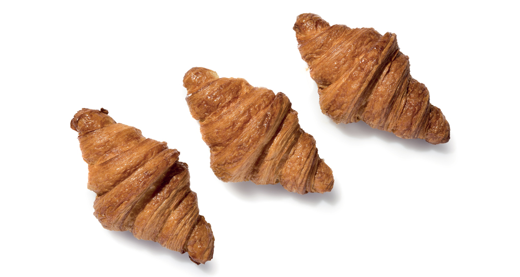 Tre croissant dorati su sfondo bianco. Pasticceria francese, colazione.