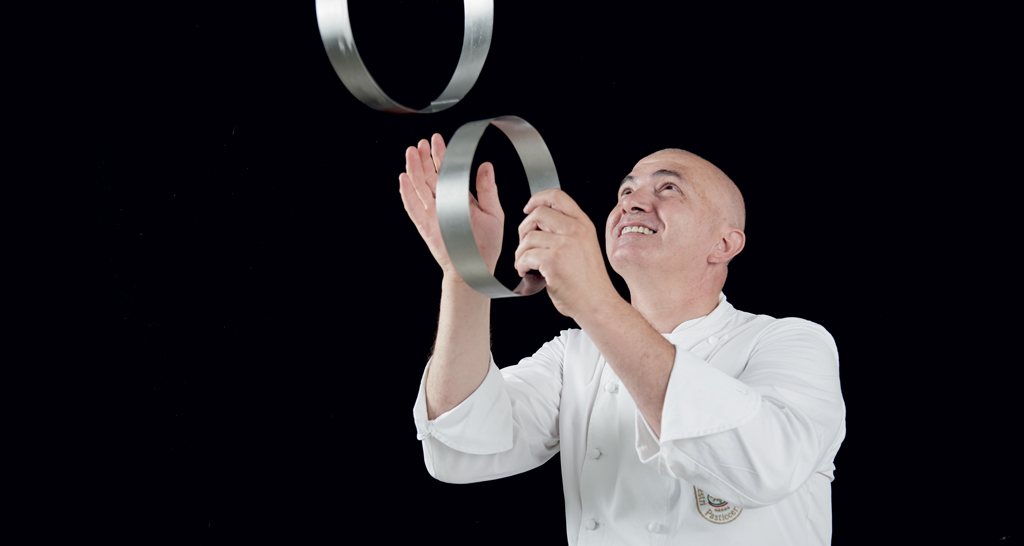Chef italiano giocoliere con anelli di metallo. Cucina creativa, alta cucina.
